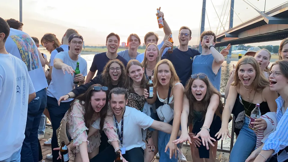 Enactus Munich members celebrating together by the river and bridge